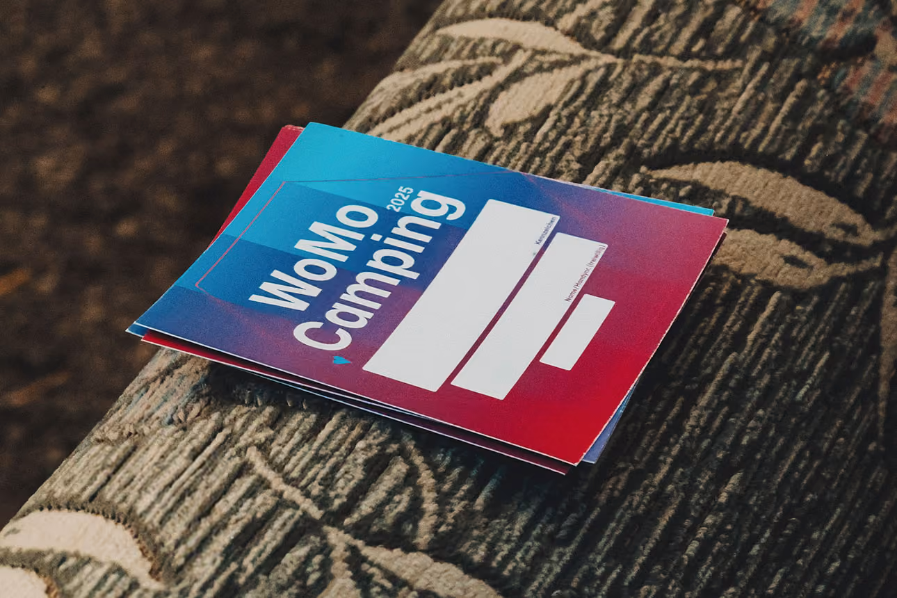 Sticker mit dem Schriftzug ‚Womo Camping‘ liegen auf einem Sofa