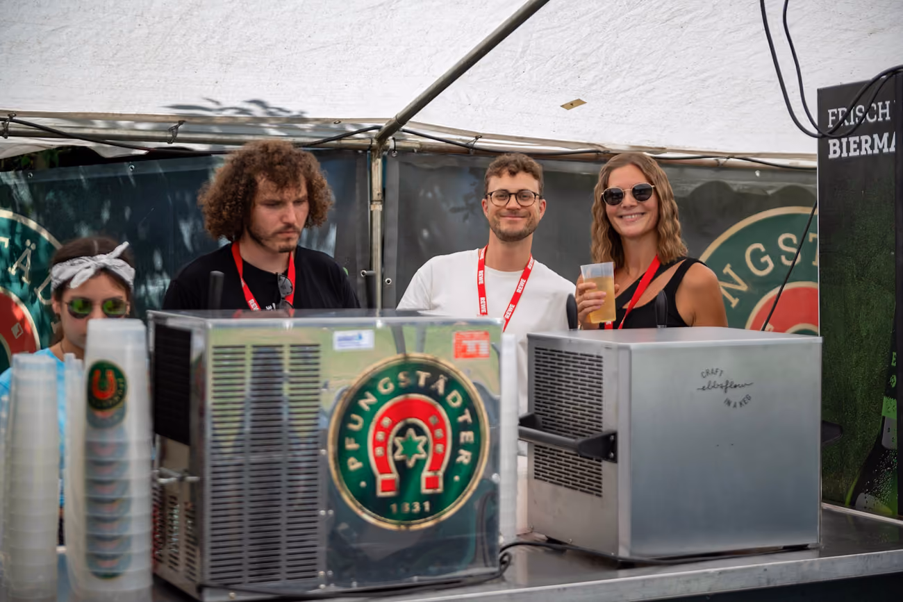 Vier Helfer stehen hinter der Theke und trinken Bier